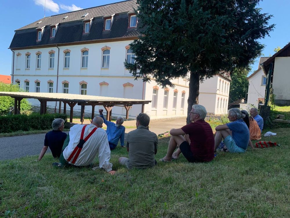 Seminargruppe sitzt im Kreis auf der Wiese vor dem Missionshaus
